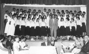 ՄԿՀ-ի երգչախումբը 1957-ի Ամավերջի հանդէսին օրը Խմբավար Պրն. Վ. Պէտէլեան բեմին վրայ Բեմէն վար, կեդրոնը նստած տնօրէն Բիւզանդ Եղիայեան 